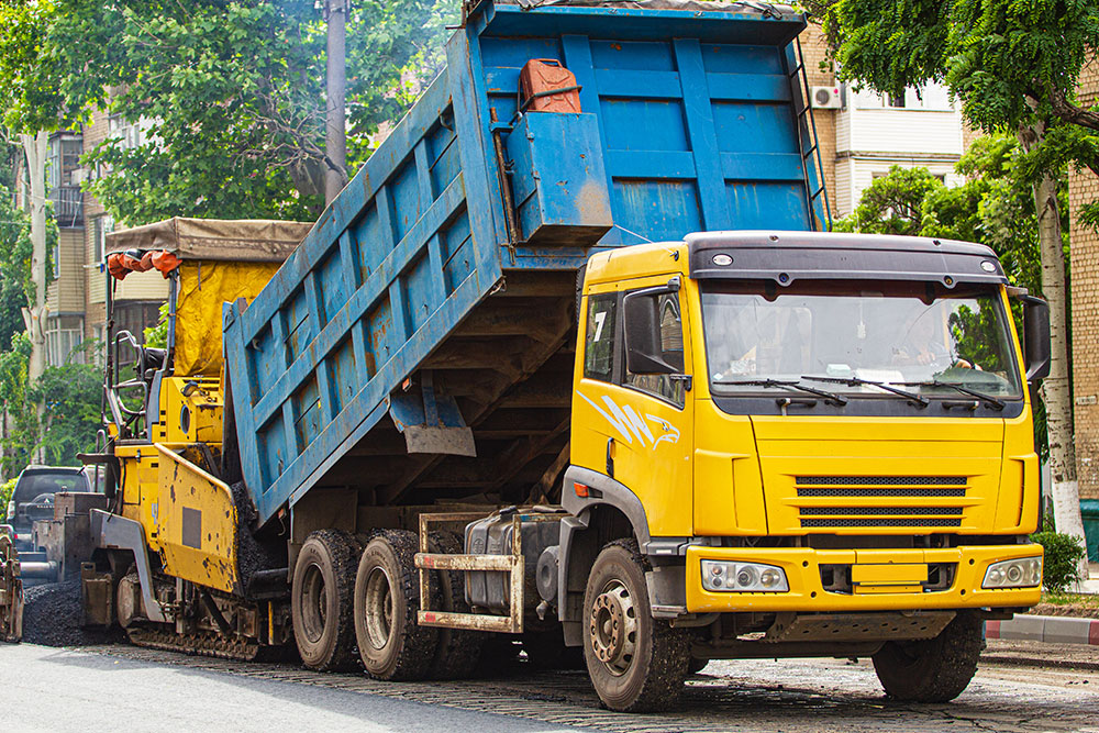 Dump truck delivering asphalt to road paving project