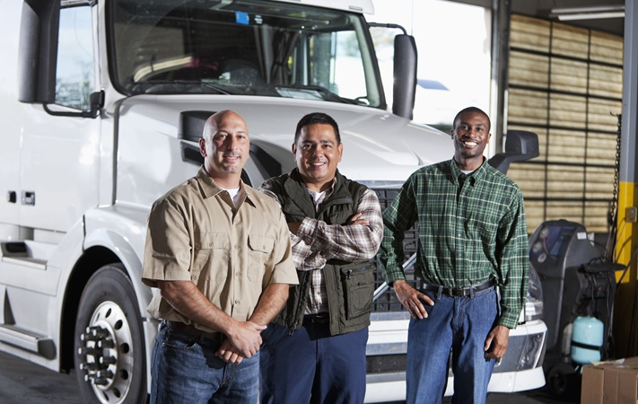 Trucking company team in front of commercial truck